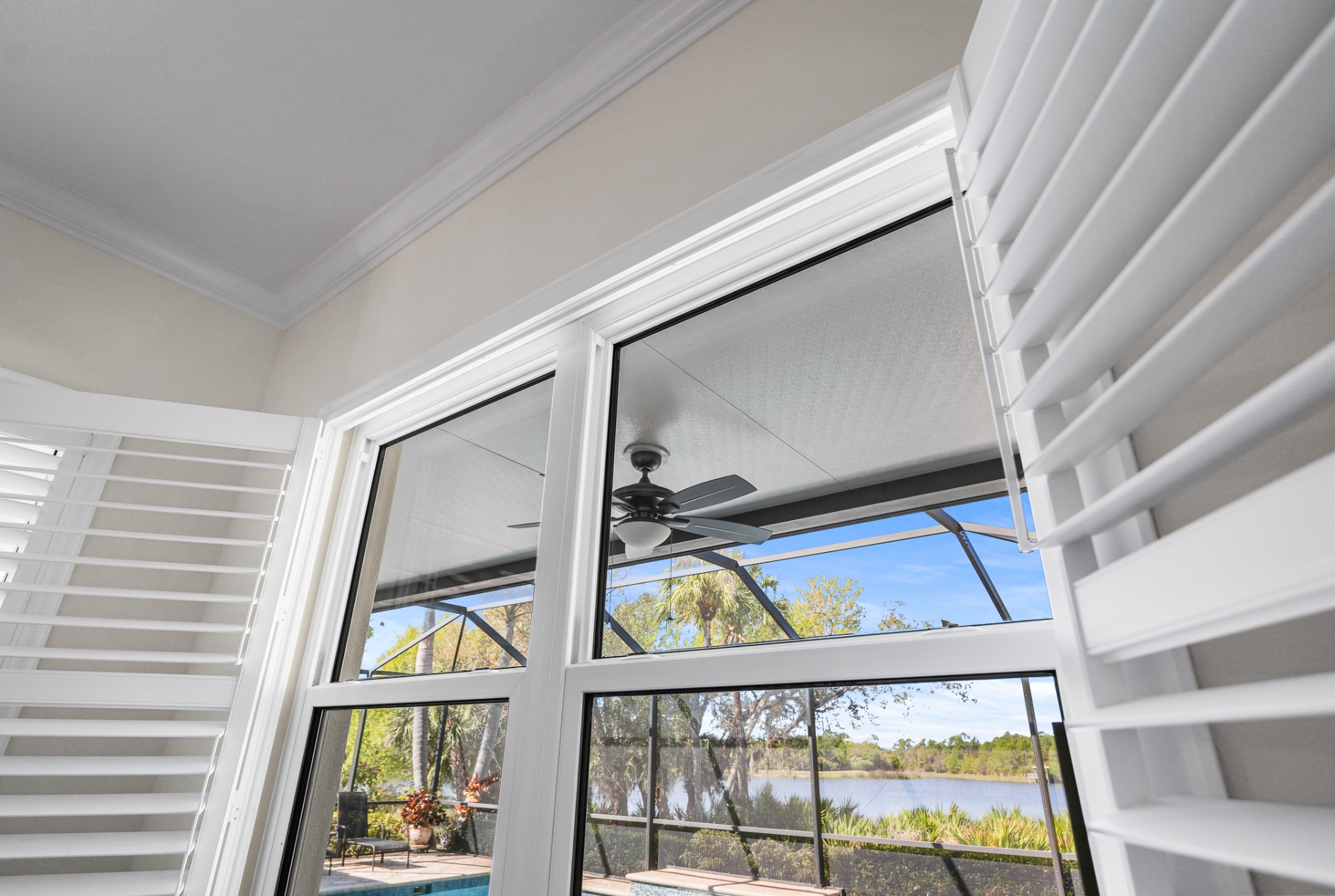 Tall impact windows overlooking pool and lake