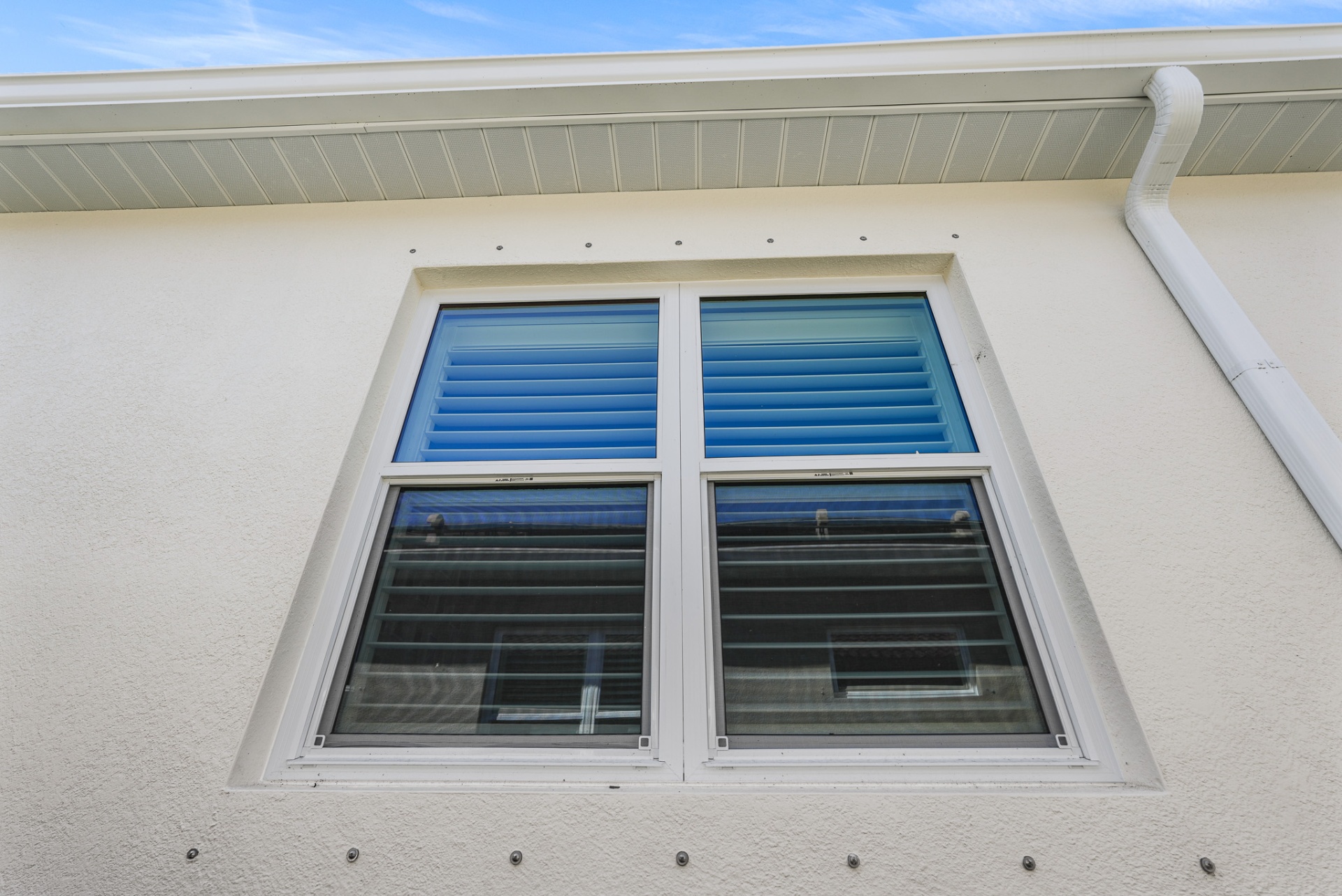 Exterior view of new impact windows installed on stucco wall