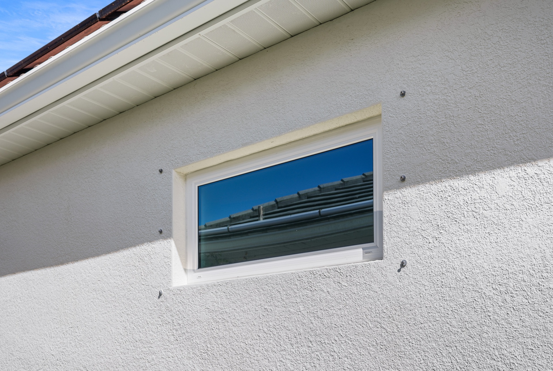Small gable-end impact window installed on stucco exterior