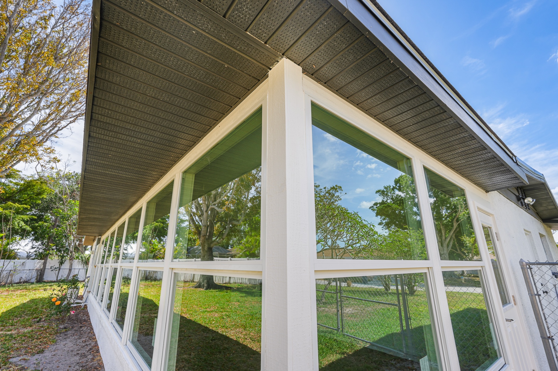 Wide-angle exterior view of sunroom impact window installation