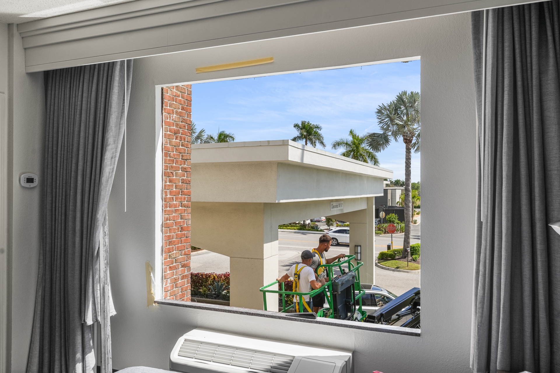 Newly installed impact picture window with view of porte-cochère and palms