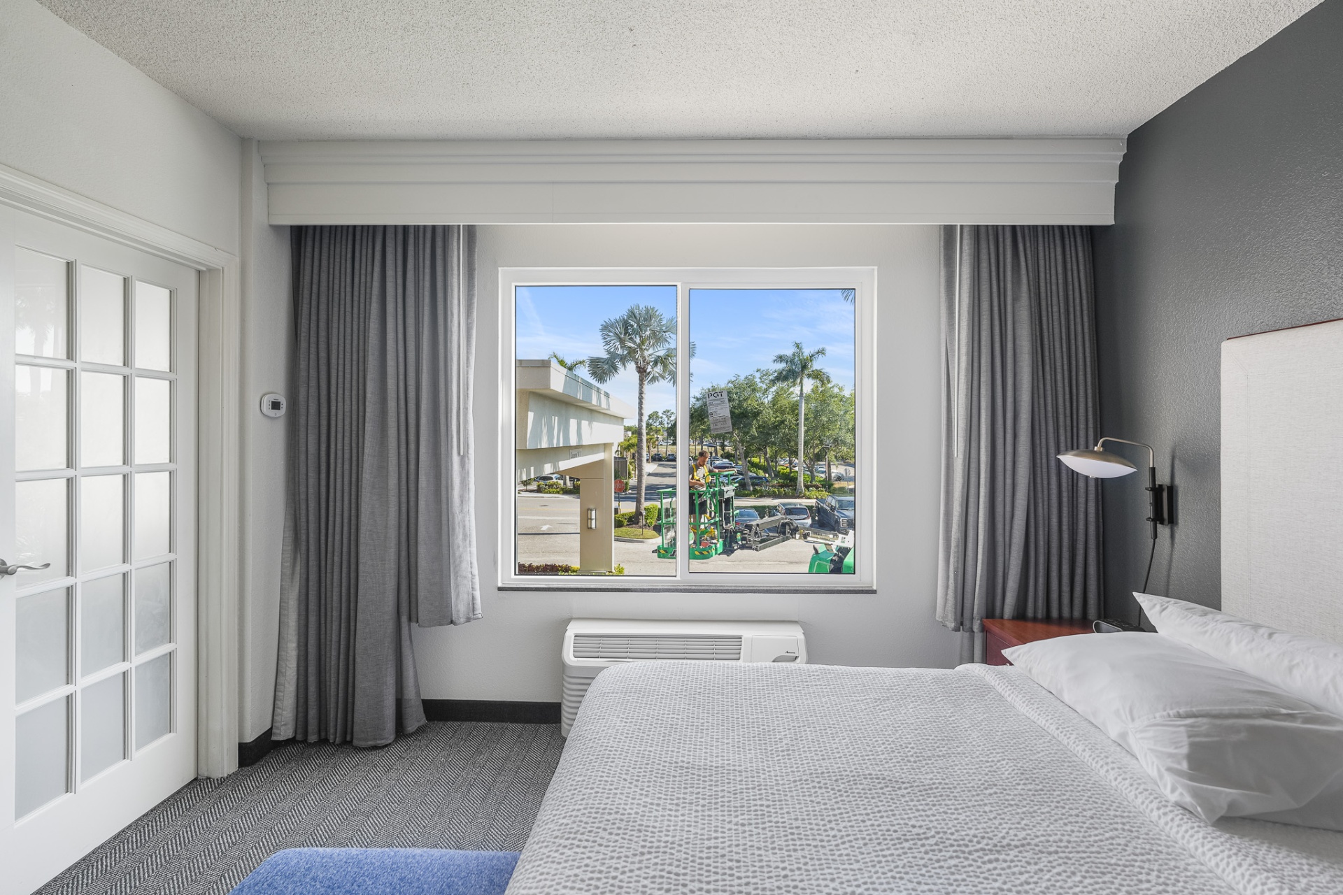 Bedroom with new impact slider window framing tropical view