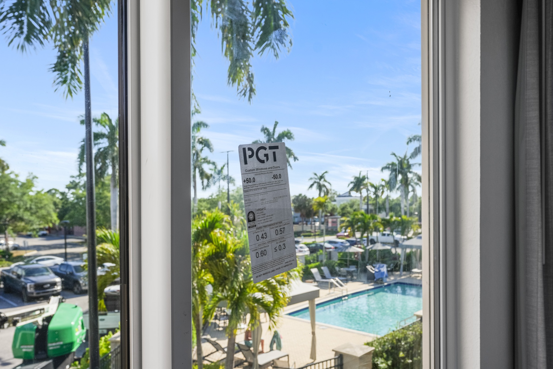 Close-up of PGT impact window label with poolside view beyond